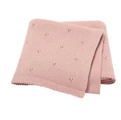 Couverture de naissance pour bébé en maille tricotée douce de couleur vieux rose, présentant un motif délicat de petits points ajourés répartis sur toute la surface et des bords travaillés.