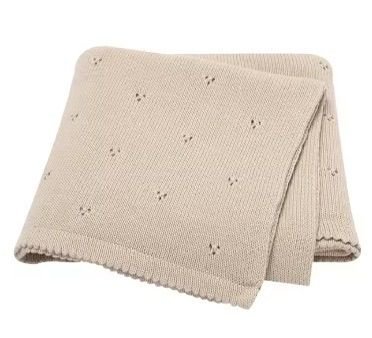 Couverture de naissance pour bébé en maille tricotée douce de couleur beige, présentant un motif délicat de petits points ajourés répartis sur toute la surface et des bords travaillés