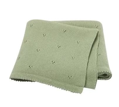 Couverture de naissance pour bébé en maille tricotée douce de couleur vert sauge, présentant un motif délicat de petits points ajourés répartis sur toute la surface et des bords travaillés.