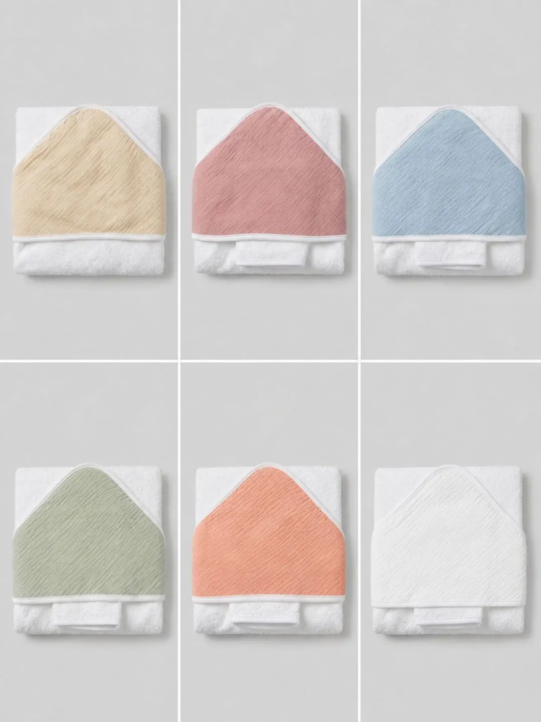 Présentation de six capes de bain pour bébé pliées, composées de tissu éponge blanc avec des capuches en mousseline déclinées en différents coloris : beige, vieux rose, bleu ciel, vert sauge, corail et blanc.